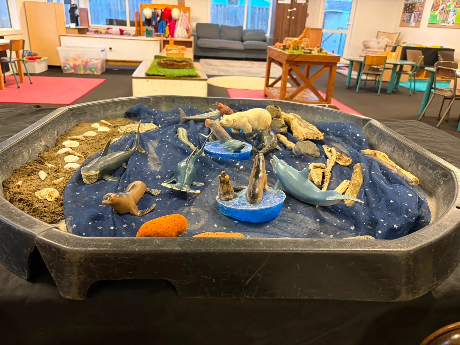 An indoor tuff tray set up as an arctic ocean with sea animals, sand and shells