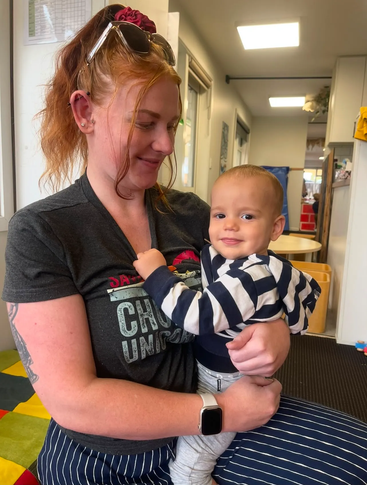 A Wonderhub kaiako holding a smiling baby in the nursery