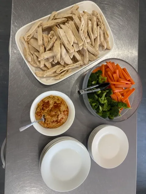 Pita bread strips with hummus and a bowl of carrot sticks and broccoli for afternoon tea