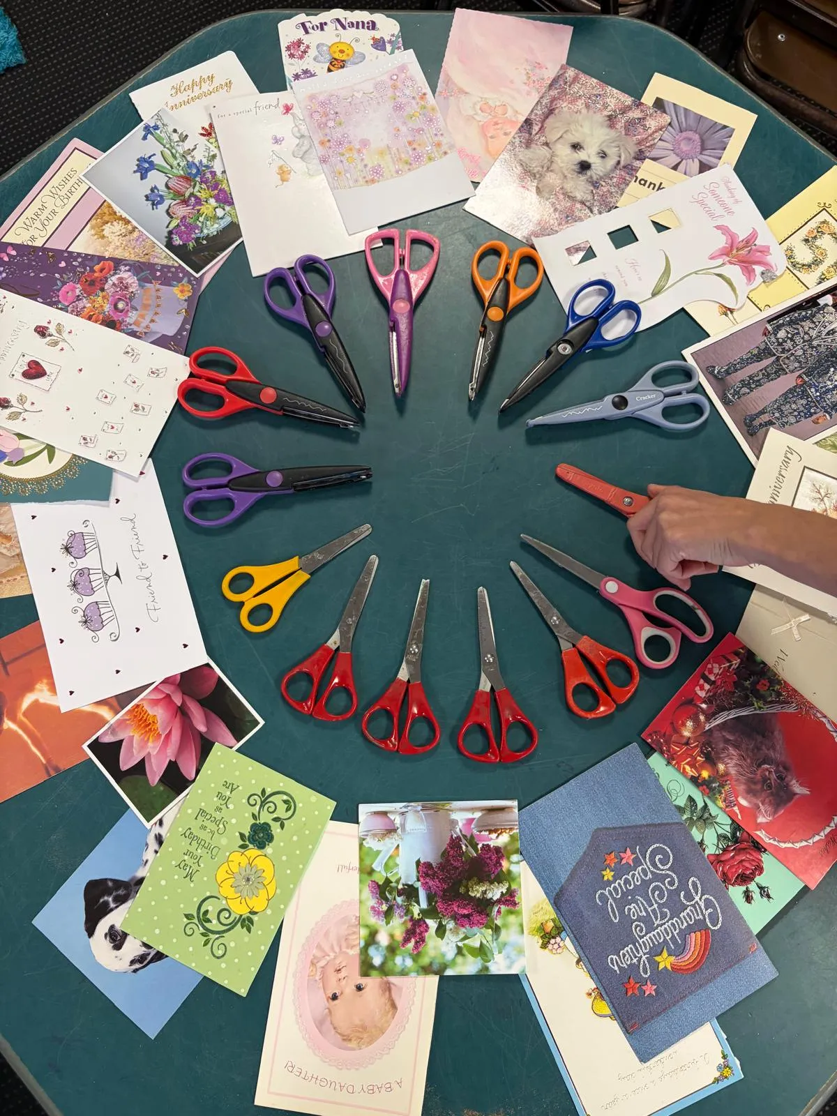 Coloured scissors arranged in a circle with greeting cards for a cutting activity