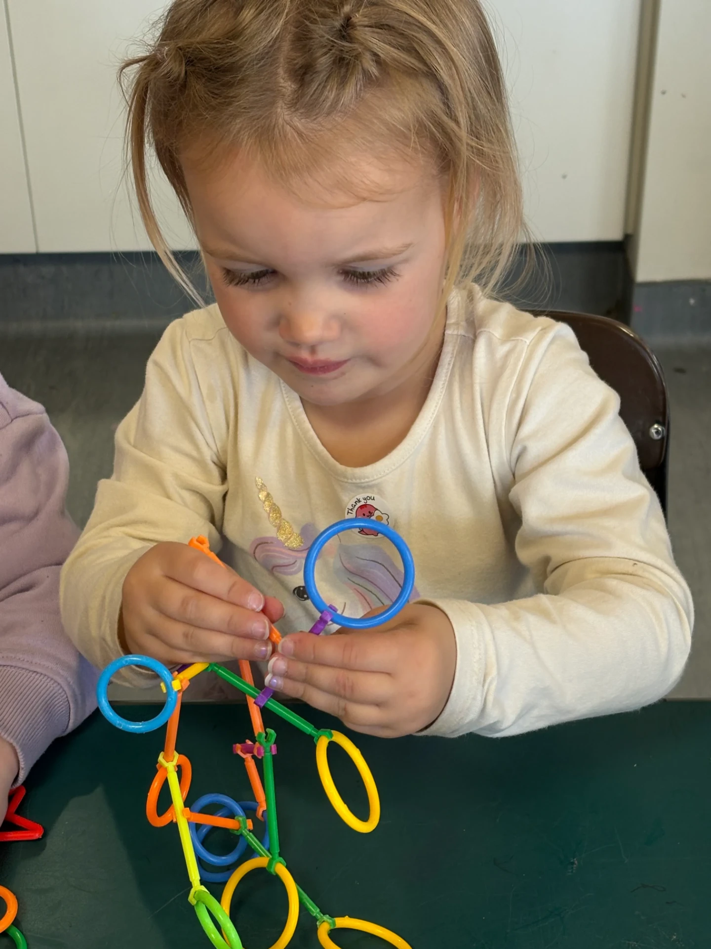 A preschooler connecting colourful building rods at the table