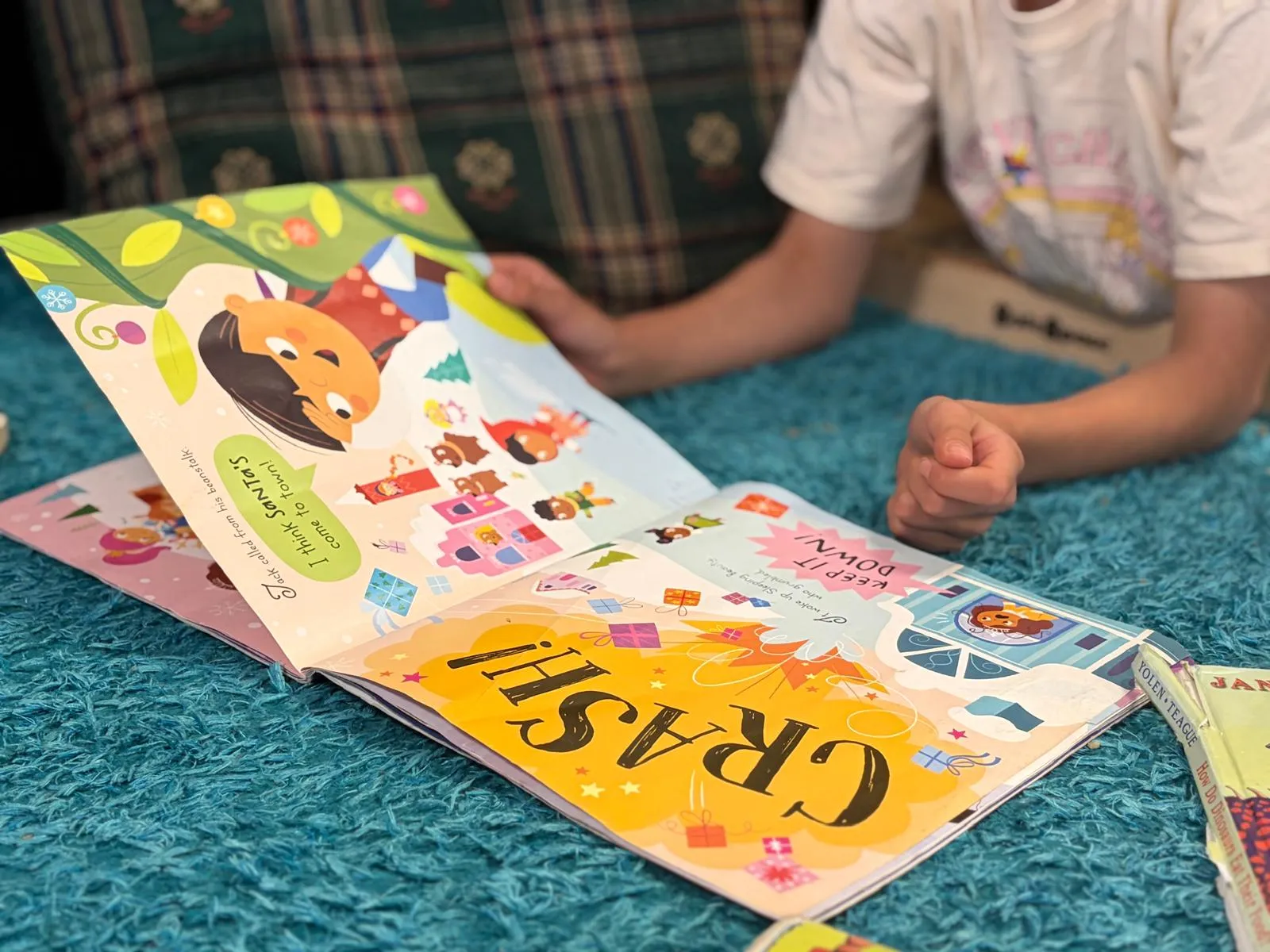 A child reading a sticker book on the mat indoors