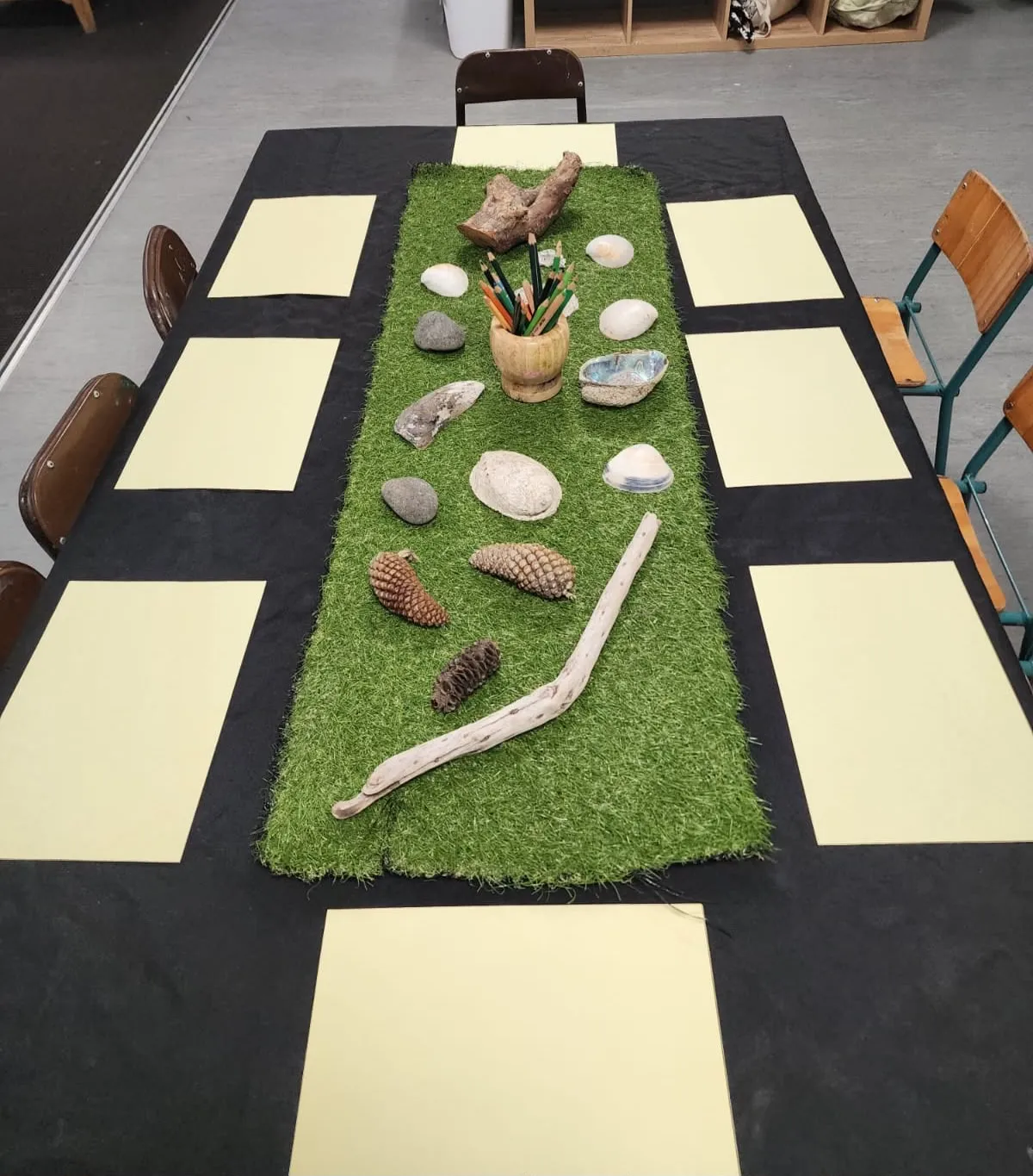 A nature table set with driftwood, shells, pine cones, stones and pencils ready for drawing